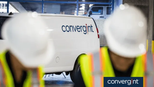 Convergint workers wearing safety gear in front of their work van