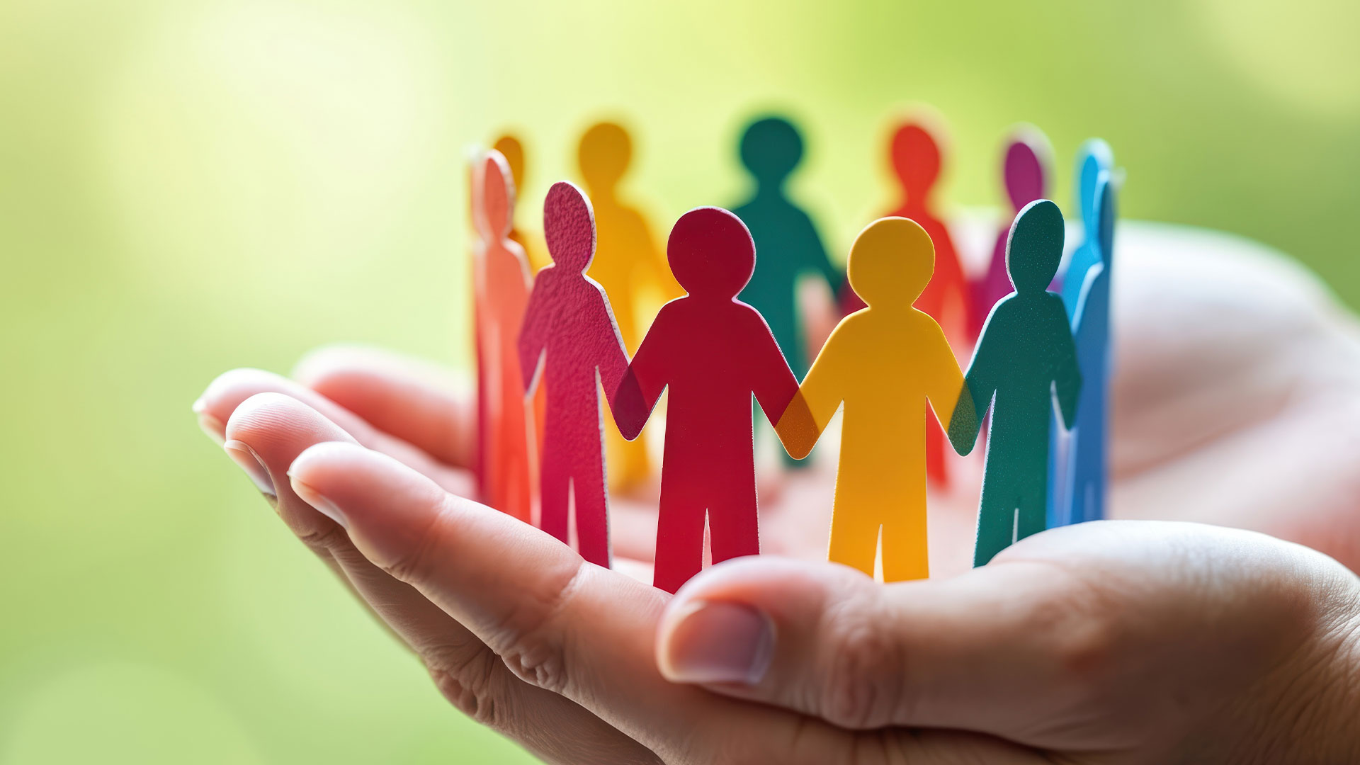 Paper people being held by two hands.