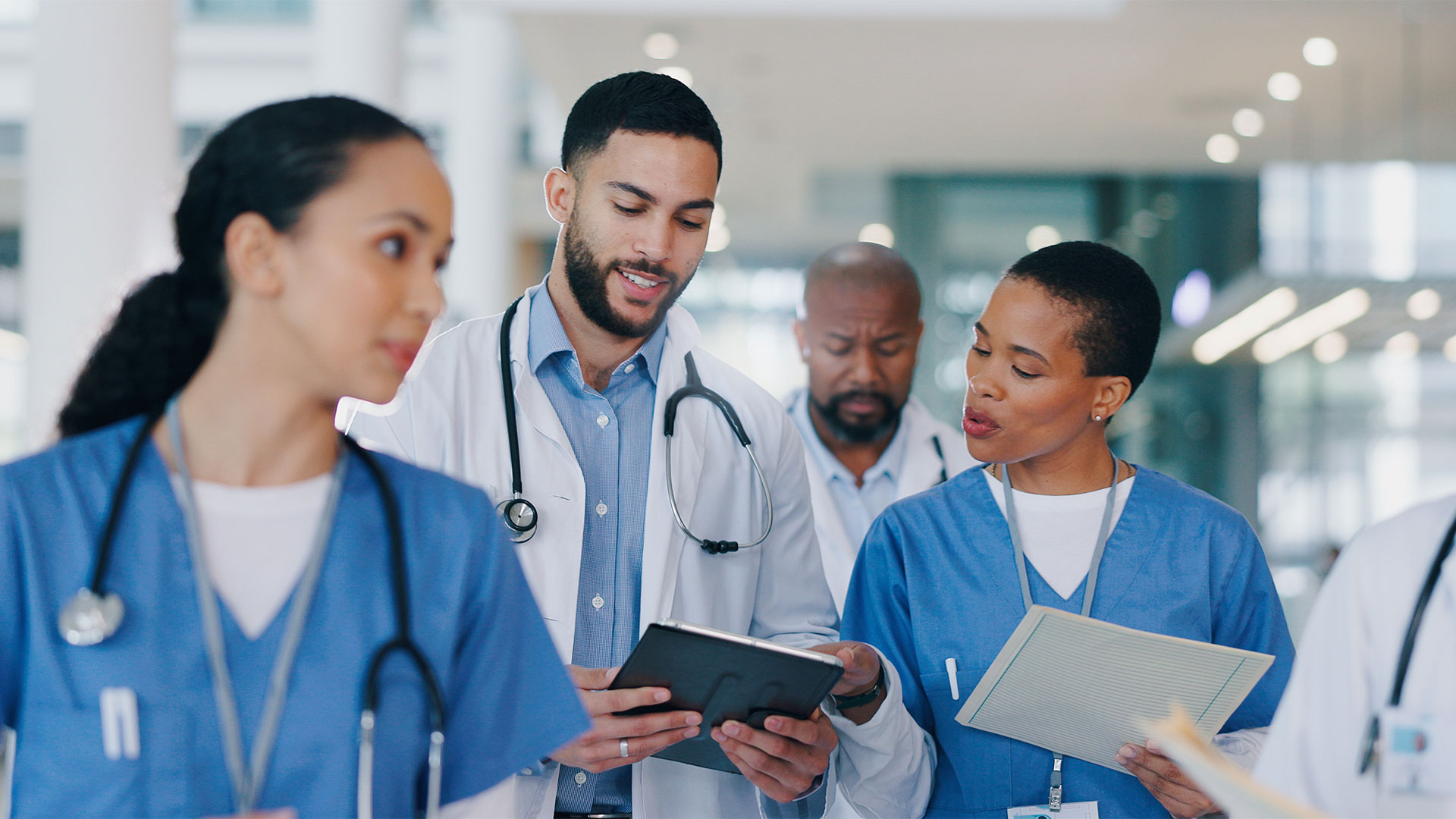 Doctors reviewing digital charts in a glass hospital