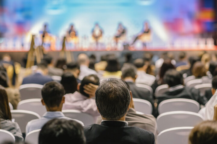 Rear view of audience listening to speakers